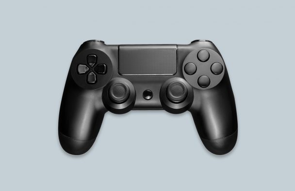A black PlayStation controller on display with a grey background.