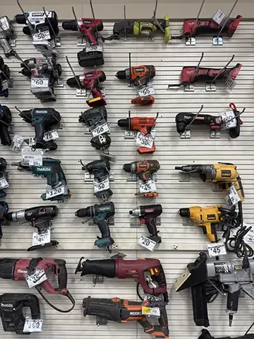 A video showing a display wall in a pawn shop featuring various power tools, including drills and grinders, organized on hooks against a pegboard background.