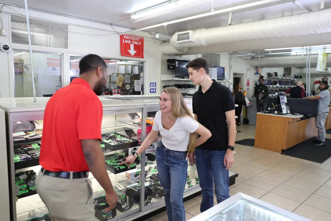 An EZPAWN team member is helping a young couple looking to purchase electronics.