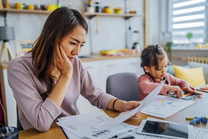 A women and a young child sitting at the table looking over bills.
