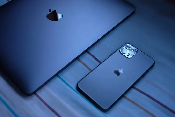 A sleek black Apple iPhone and an iPad are resting on a table.