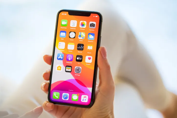 A women is holding an iPhone with the screen lit up.
