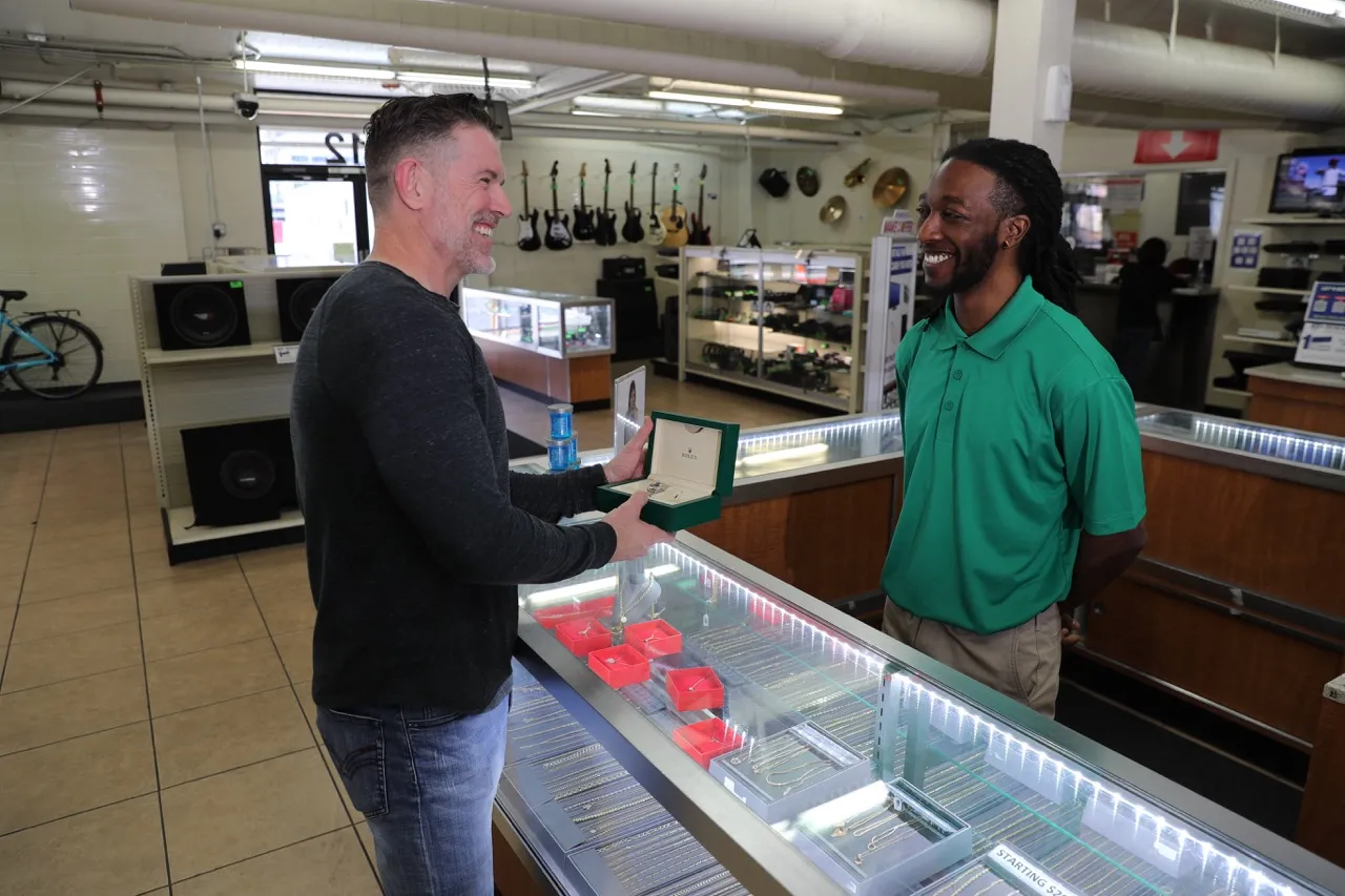 An EZPAWN team member is assisting a customer at the jewelry counter with a watch.